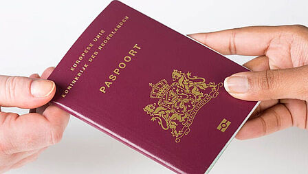 Paspoort die door twee verschillende handen wordt vastgehouden.