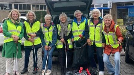Groep vrijwillige afvalrapers met hesjes, prikstokken en gevulde vuilniszakken