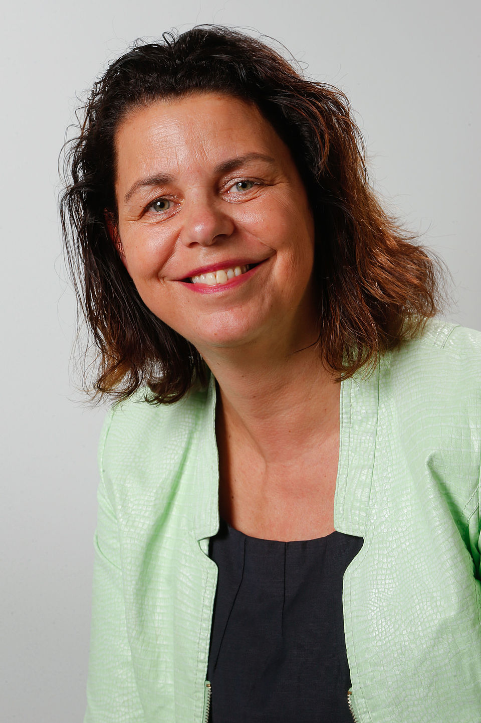 Portretfoto van mevrouw Andrea van Langen. Mevrouw van Langen draagt een licht limegroen jasje met daaronder een donkerblauw shirt.